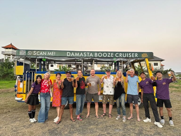 A large group of guests and team members posing beside the yellow Damasta Booze Cruiser.