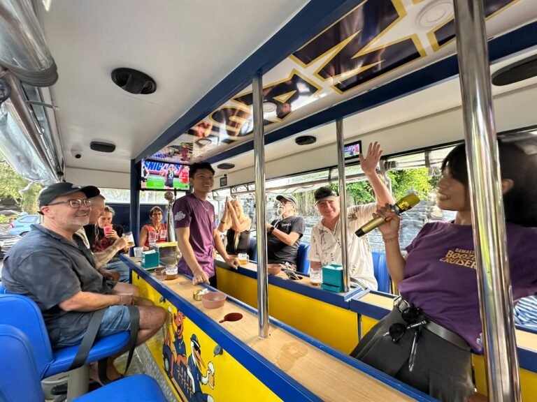 Guests seated around the onboard bar of the yellow Damasta Booze Cruiser in Seminyak.