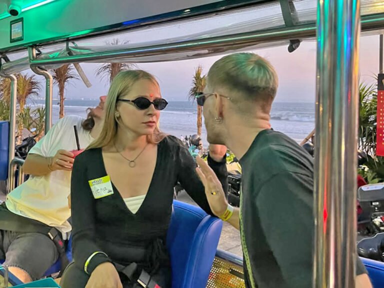 Two guests wearing sunglasses chatting on blue seats inside Damasta Booze Cruiser.